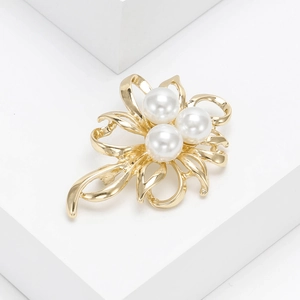 Detail of floral gold brooch with three large white pearls on a minimalist white stand