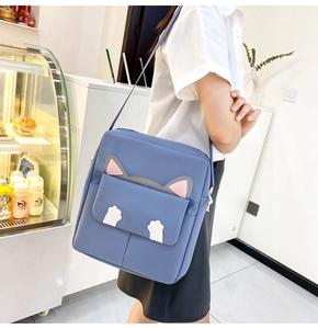 Blue crossbody bag with cute cat design worn by a model in a bright indoor setting
