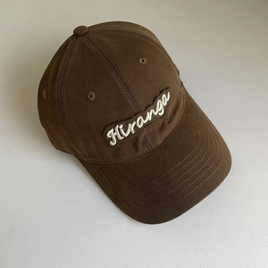 Close-up of Hiranga 3D embroidery on deep brown cotton baseball cap fabric texture