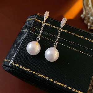 Detailed macro view of zircon-inlaid earrings with elegant white pearls on a jewelry box