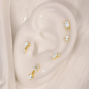 Détail de cinq clous d'oreilles dorés avec opale présentés sur un modèle d'oreille en silicone