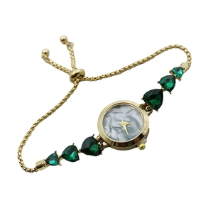 Gold bracelet watch with marble dial and emerald heart gems on a snake chain
