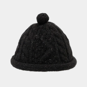 Close-up of black cable knit beanie with silver fiber details and top pompom