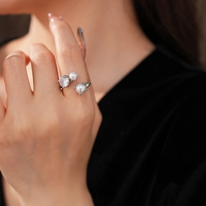 Détail d'une bague ajustable en argent ornée de perles doubles et d'un zircon au doigt