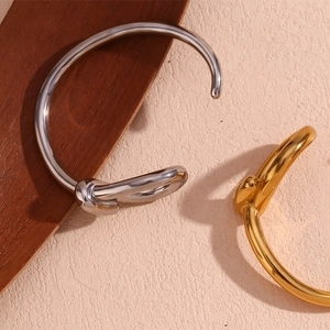 Detail of twisted knot open cuff bracelets in polished gold and silver finishes
