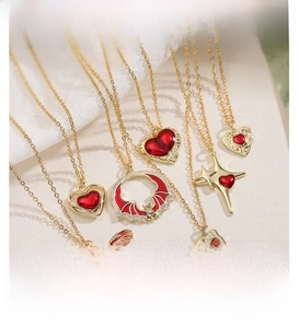 Macro shot of gold-plated necklaces with red enamel heart, dragonfly, and star pendants