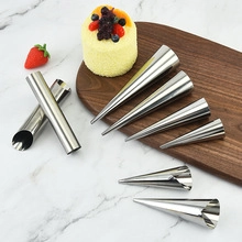 Close-up of conical stainless steel pastry molds on wooden board for professional baking