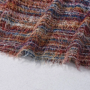 Close-up of multicolor woven fabric with long fringe detail and textured fibers