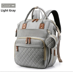 Detail view of light gray quilted baby diaper bag with leather pullers and side pouch