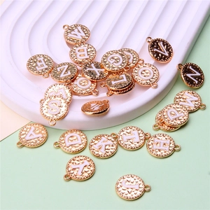 Close-up of golden round alphabet charms with white enamel letters A-Z for DIY jewelry