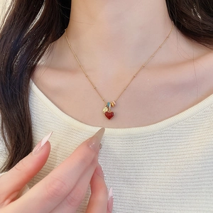 Detail view of a 18k gold plated necklace with a red heart pendant on a model's neck