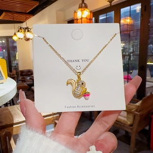 Detail of a gold-plated squirrel pendant necklace with crystal pave on a thank you card