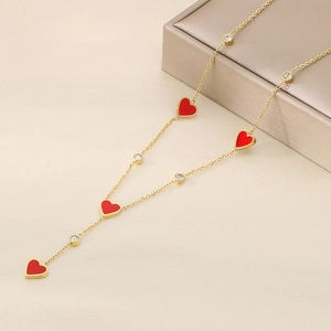 Detail of gold necklace featuring red heart pendants and sparkling zircon accents