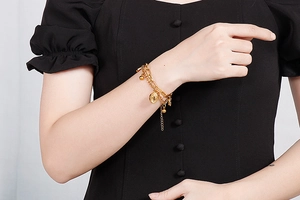 Detailed view of gold double-layered sunray coin bracelet on a model's wrist