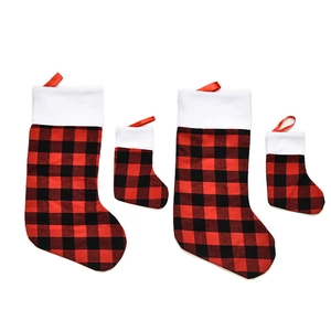 Set of red and black buffalo plaid Christmas stockings in large and small sizes on white backdrop
