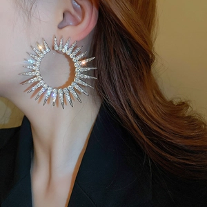 Macro shot of oversized silver hoop earrings with sparkling rhinestones in radial sunburst design