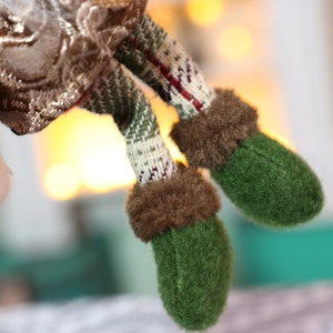 Macro delle gambe in maglia scozzese e stivali di feltro verde del ciondolo di Natale