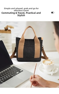 Canvas tote bag in black with brown straps shown on a desk with a laptop and coffee