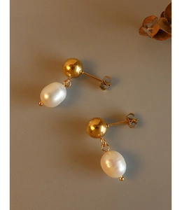 Detail of elegant gold ball stud earrings with unique baroque pearl pendants