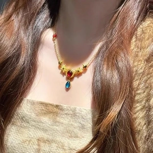 Neo-Chinese style gold necklace with red and blue resin gemstones on a delicate chain
