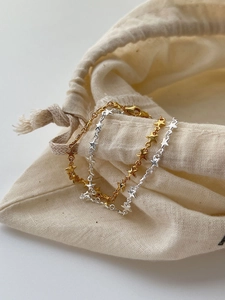 Detailed view of S925 sterling silver star bracelets in gold and silver finish on linen bag