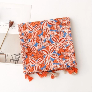 Detailed close-up of gardenia floral print linen scarf with orange and blue fringe edge