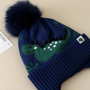 Winter knit dinosaur hat for boys with navy blue fleece lining and a fuzzy pompom
