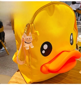 Detail of yellow canvas duck backpack with a cute dog pendant on a wooden cafe table
