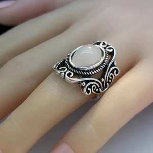 Dettaglio di anello vintage in argento con pietra di luna rosa e motivi floreali traforati