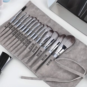 Detail of 13 marble makeup brushes stored in a grey functional roll-up pouch