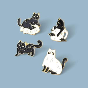 Detail of four black and white enamel cat pins featuring spooky ghosts and celestial motifs