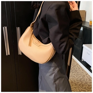 Dettaglio della borsa a mezzaluna beige che mostra la trama a grana e la tracolla in pelle
