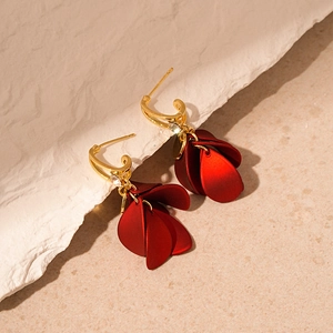 Red petal drop earrings with gold metal hooks and small rhinestones on stone background