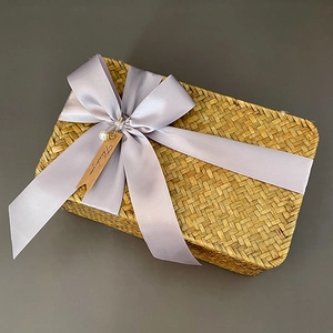 Detail of woven seagrass gift box with purple ribbon bow and thank you tag decoration