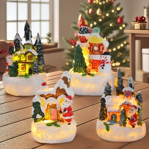 Close-up of lighted Christmas resin miniature houses with Santa and snowman on wood