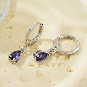 Detailed view of silver hoop earrings featuring a pear-cut purple zirconia pendant