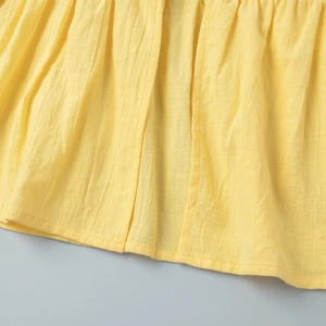 Detailed macro view of yellow linen fabric showing natural texture and ruffled hemline