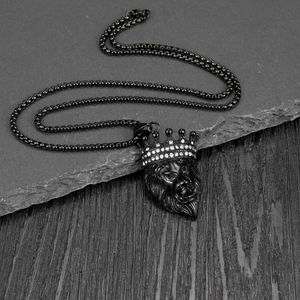 Macro shot of a black punk lion head pendant with diamonds on a textured rock surface