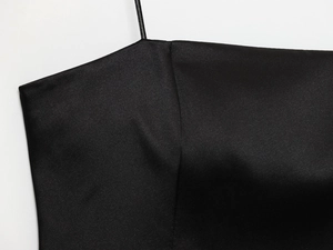 Détail du col d'une robe en satin noir avec dentelle et fines bretelles spaghetti