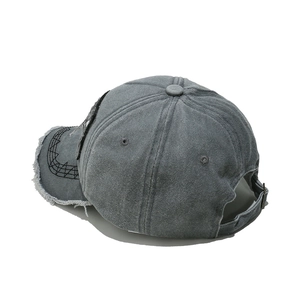 Detail of distressed grey washed denim baseball cap with frayed edges and vintage texture