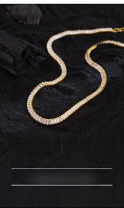 Macro shot of luxury geometric necklace with baguette-cut zircons on black sand background