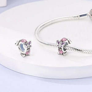 Macro shot of silver butterfly charm with purple enamel and zircon inlay on snake chain