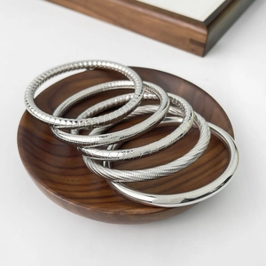 Macro view of five textured silver titanium steel bangles on a vintage wooden tray