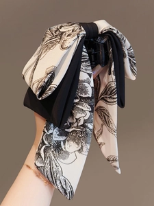 Détail de la pince à cheveux nœud en soie avec motif floral noir et blanc