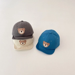 Detail of baby bear baseball caps in dark grey, beige, and blue soft cotton fabric