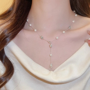 Detail of Y-shaped silver necklace with irregular pearls on a woman's collarbone