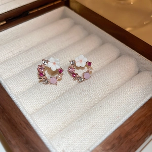 Dettaglio macro di orecchini a ghirlanda con strass rosa e petali bianchi
