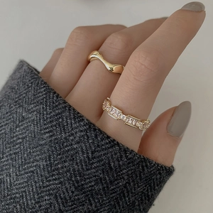 Gros plan sur des bagues dorées empilées avec zircon rectangulaire et design ondulé