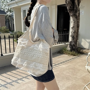 Gros plan sur le sac fourre-tout en dentelle crème montrant le tissu plissé et le canevas