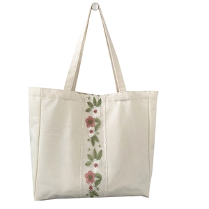 Borsa tote in tela minimalista con ricami floreali e finiture in pizzo su sfondo bianco